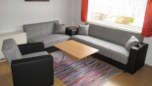 A modern living room with a grey sofa, a wooden coffee table, and a colorful striped rug. - Haus im Grünen by Interhome (Marktgraitz)