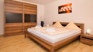 Ein ordentlich eingerichtetes Schlafzimmer mit einem hölzernen Bettgestell, einem Nachttisch mit Lampe und einem großen Kleiderschrank mit Spiegel.