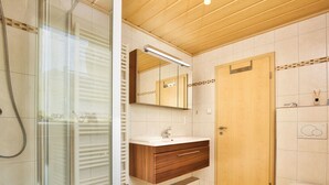 Ein modernes Badezimmer mit Duschkabine aus Glas, Holzwaschtisch und Toilette.
