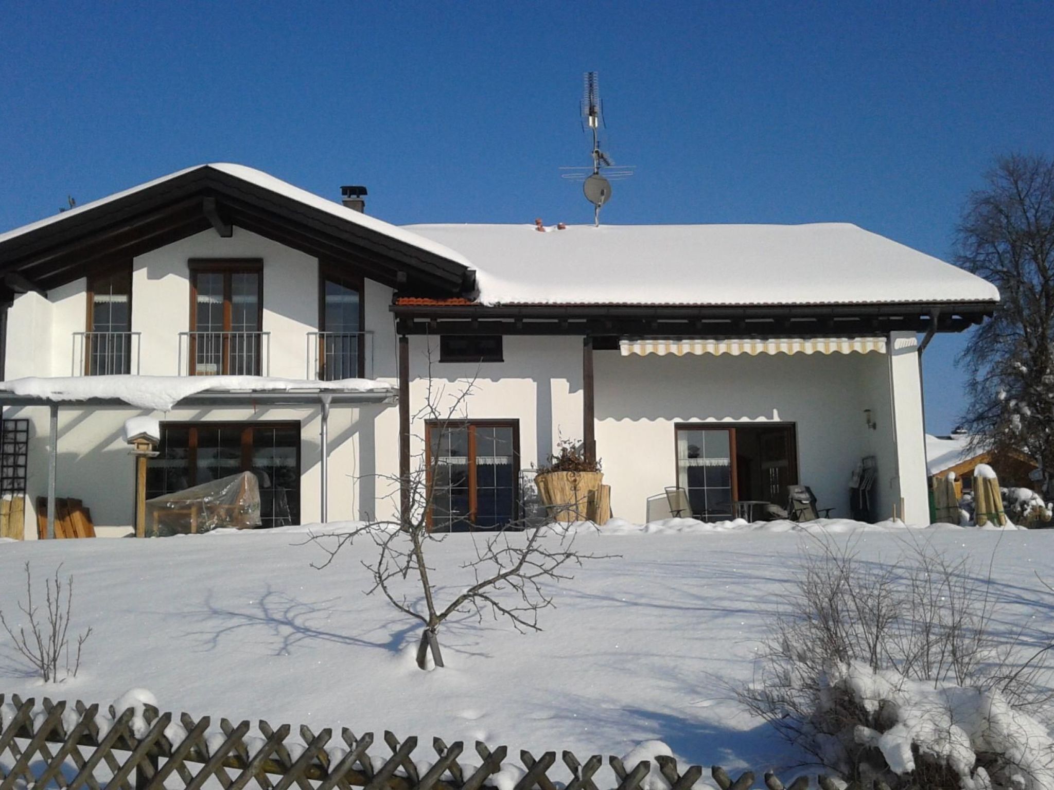 A two-story house with a snow-covered roof and a balcony.