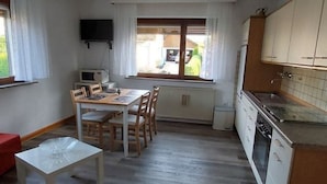 Una cocina funcional con una mesa, sillas, un refrigerador pequeño y un microondas.