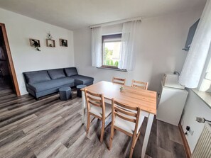 Ein gemütlicher, kompakter Wohnbereich mit einer Couch, einem Esstisch und einer kleinen Küchenzeile.