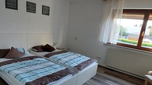 Un dormitorio con dos camas, una ventana con cortinas y decoración inspiradora en la pared.