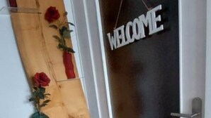 Una puerta con un letrero que dice 'WELCOME' y un panel de madera con rosas rojas.