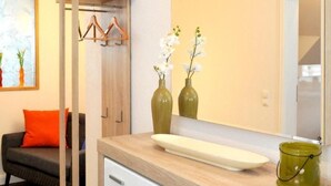 A modern bathroom with a wooden vanity, white drawers, a large mirror, and two orchid vases. - in Feldmannshof mit Grill und Garten by Interhome (Drolshagen)