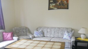Ein Wohnzimmer mit einer Couch, einem Couchtisch und einem Bild an der Wand.