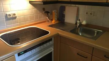 Een koelkast, een oven, kookgerei, borden en bestek