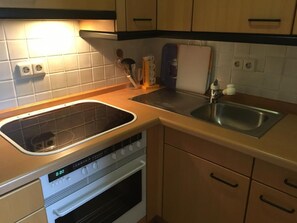 Een koelkast, een oven, kookgerei, borden en bestek