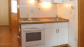 Een kleine keuken met witte kastjes, een fornuis en een spoelbak.