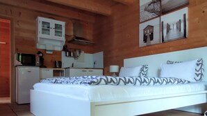 A bedroom with a bed, a kitchenette, and wooden ceiling beams. - Studio Blockhaus by Interhome (Bernau)