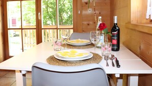 A wooden dining table with plates, glasses, and a bottle of wine. - Studio Blockhaus by Interhome (Bernau)