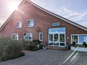 A two-story brick building with a large glass door entrance, a satellite dish, and a number '24' sign. - Landambiente Halbemond by Interhome (Hage)