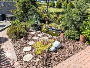 A garden with a pond, stepping stones, and various plants. - Landambiente Halbemond by Interhome (Hage)