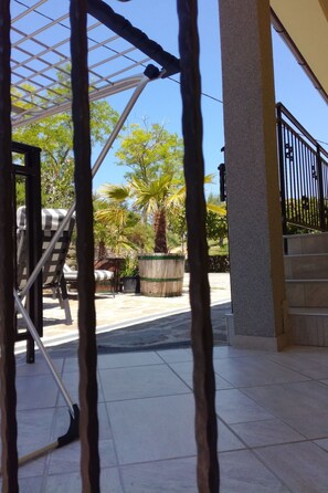 Uma área externa coberta com pérgola, móveis de exterior e uma escadaria que leva a um andar superior.
