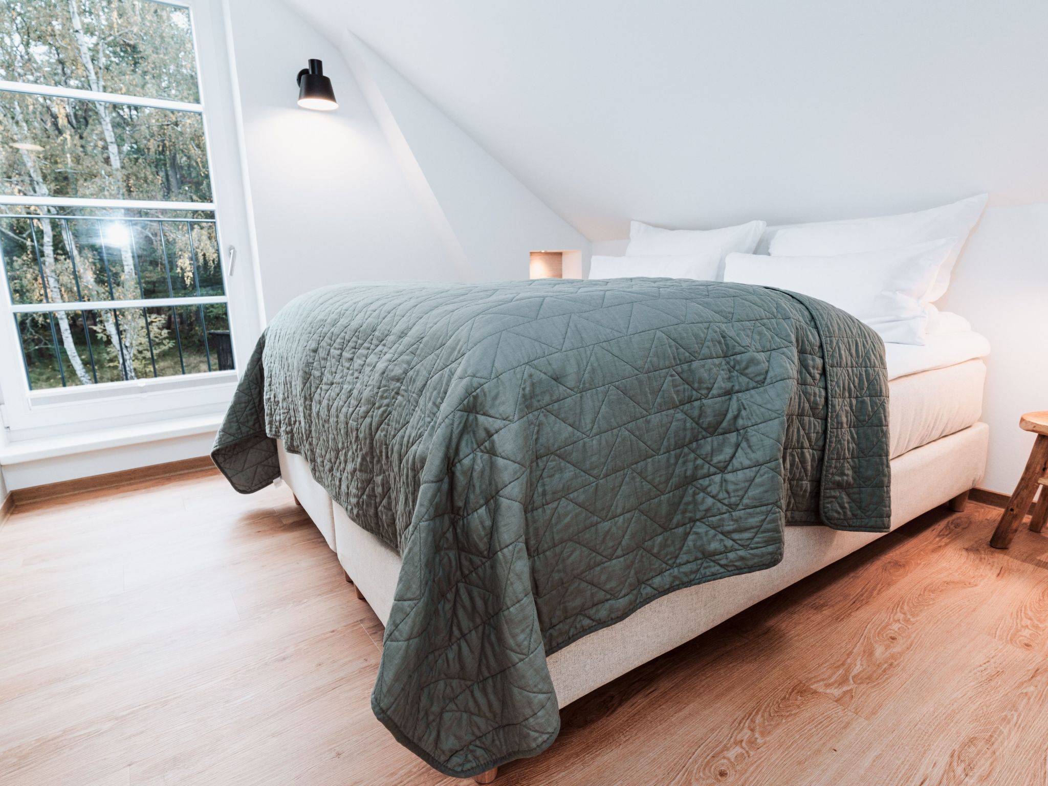Un dormitorio con cama, ventana y mesita de noche.