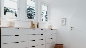 Een witte kamer met een groot kast, een raam en een deur.