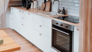 Een moderne keuken met witte kasten, een houten aanrecht, een roestvrijstalen spoelbak en een oven.