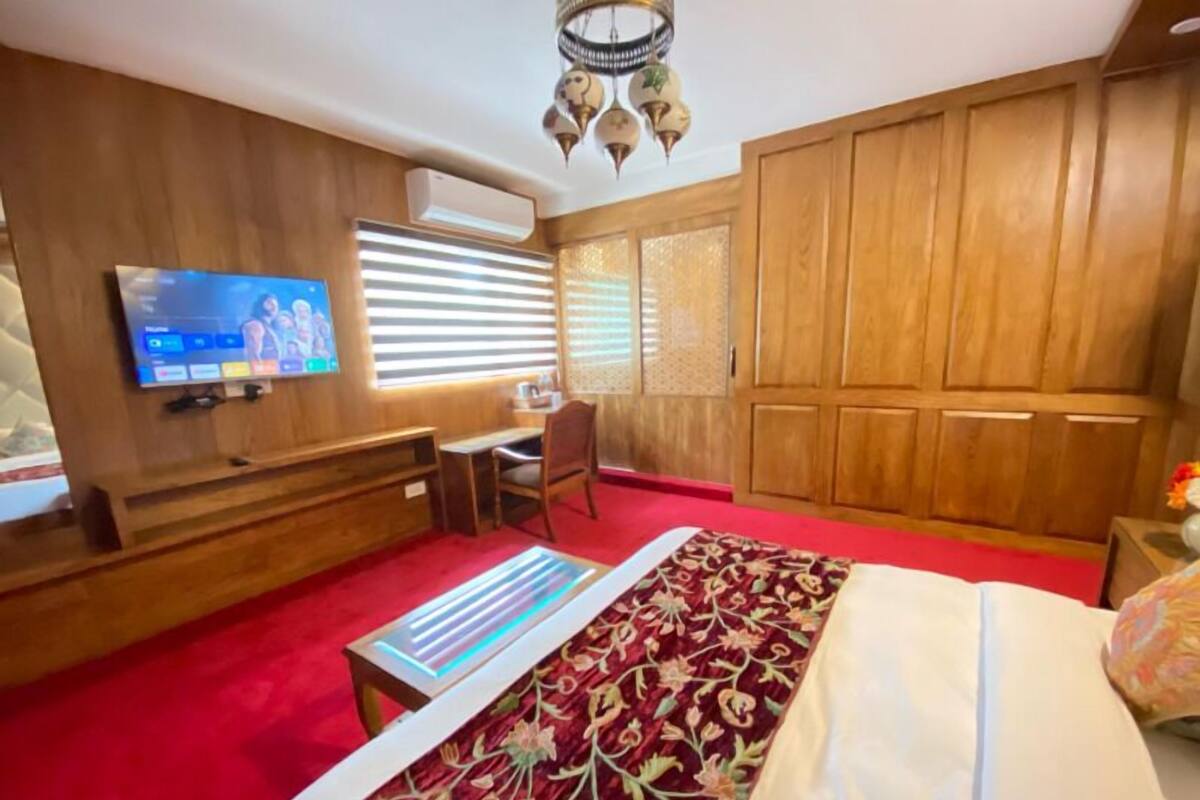 Un dormitorio con televisión, escritorio, silla, cama y armario.