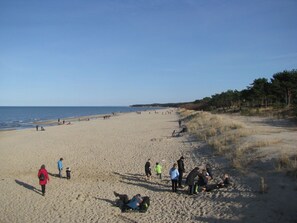 Une vaste plage de sable où l’on voit des gens se promener et s’asseoir.