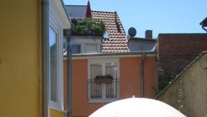 An outdoor patio with a table and chairs, an umbrella, and a yellow building in the background. - Moderne Ferienwohnung mitten in Greifswald by Interhome (Greifswald)