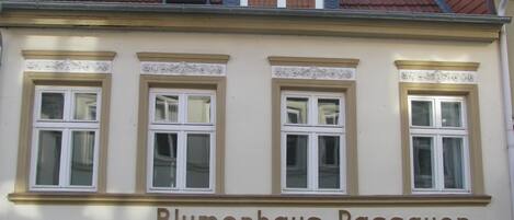 Ein Gebäude mit drei Fenstern und einem Schild, auf dem 'Blumenhaus Passauer' steht.