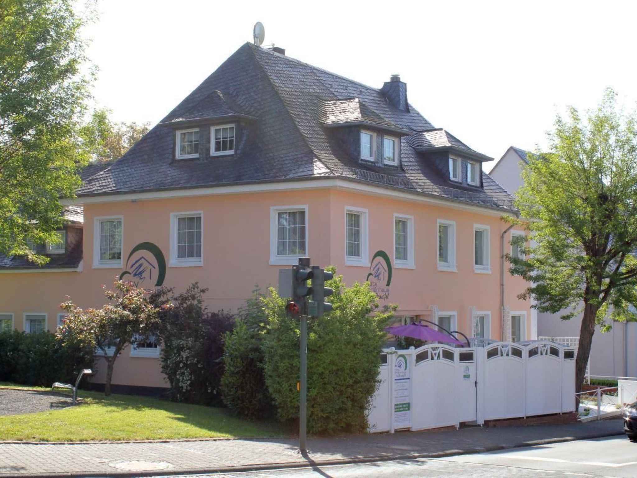 A two-story building with a peach-colored facade, multiple windows, and a satellite dish on the roof.