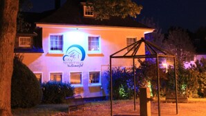 A house with a sign reading "City Ferienhaus Vulkaneifel" illuminated at night. - Schöne Ferienwohnung in Daun mit Garten by Interhome (Daun)