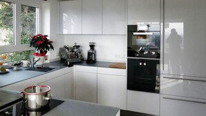 Ett modernt kök med vita skåp, ett svart kylskåp och en kaffemaskin.