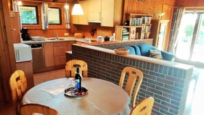 Een gezellige keuken met houten kastjes, een eettafel met stoelen en een klein keukeneiland met zitplaatsen.