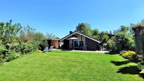 Een gelijkvloers huis met een verzorgd gazon en een terras.