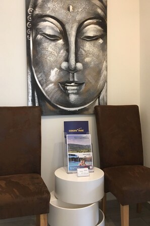 A reception area with a large metal sculpture, a brochure stand, and two brown chairs. - Stadtferienwohnung by Interhome (Müllheim)
