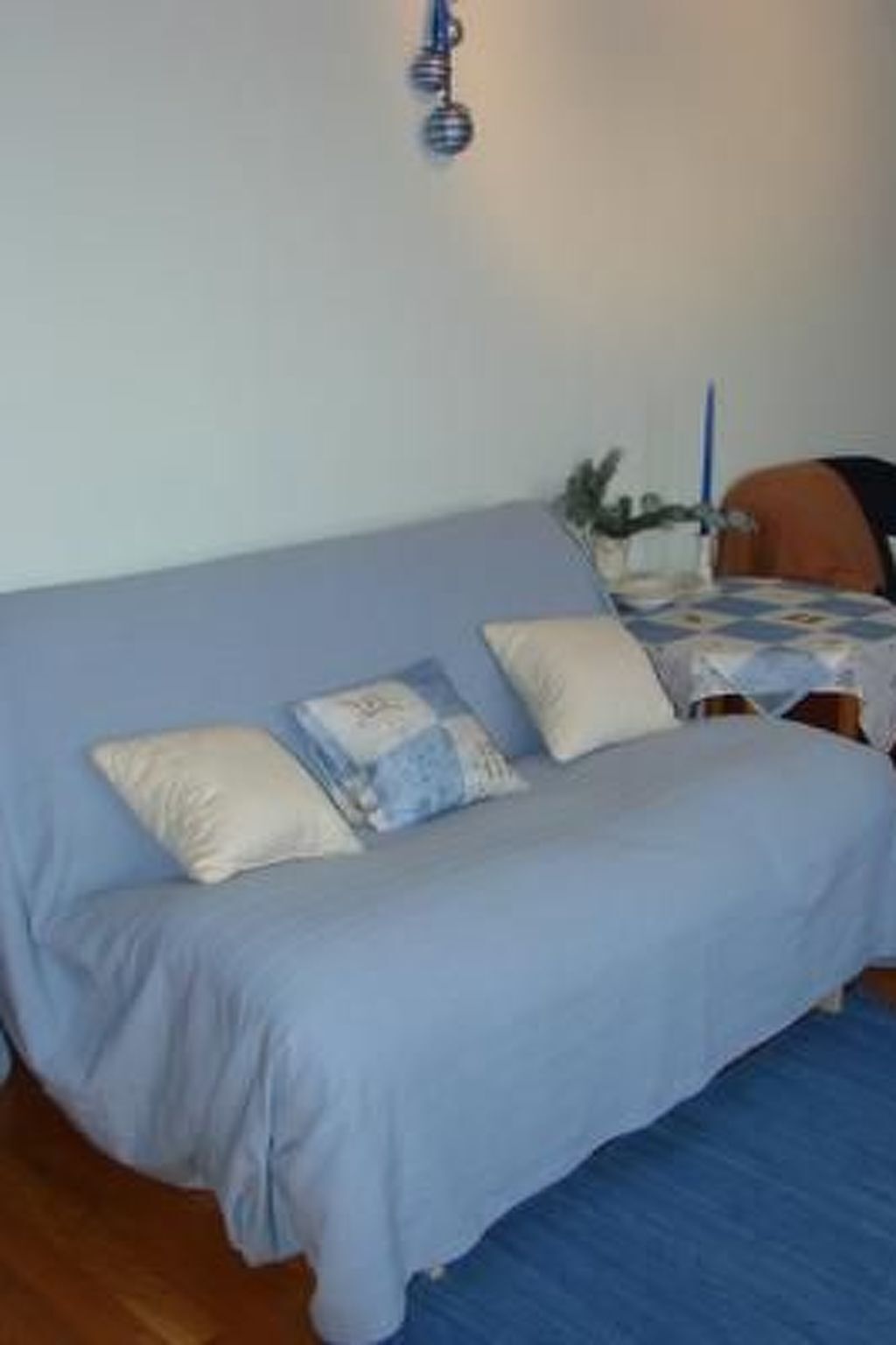 Et værelse med en lyseblå sofa, et lille bord med et blåt duge og en stol.