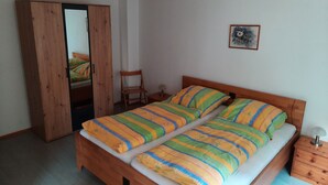 Une chambre à coucher avec un lit en bois, une armoire en bois, une chaise et une petite table de chevet.
