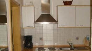 Une cuisine de taille réduite, avec des meubles blancs, une cuisinière, un évier et une machine à café.