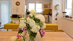 Ein modernes Wohnzimmer mit einem Holztisch, einem Blumenstrauß und einer gelben Bank.
