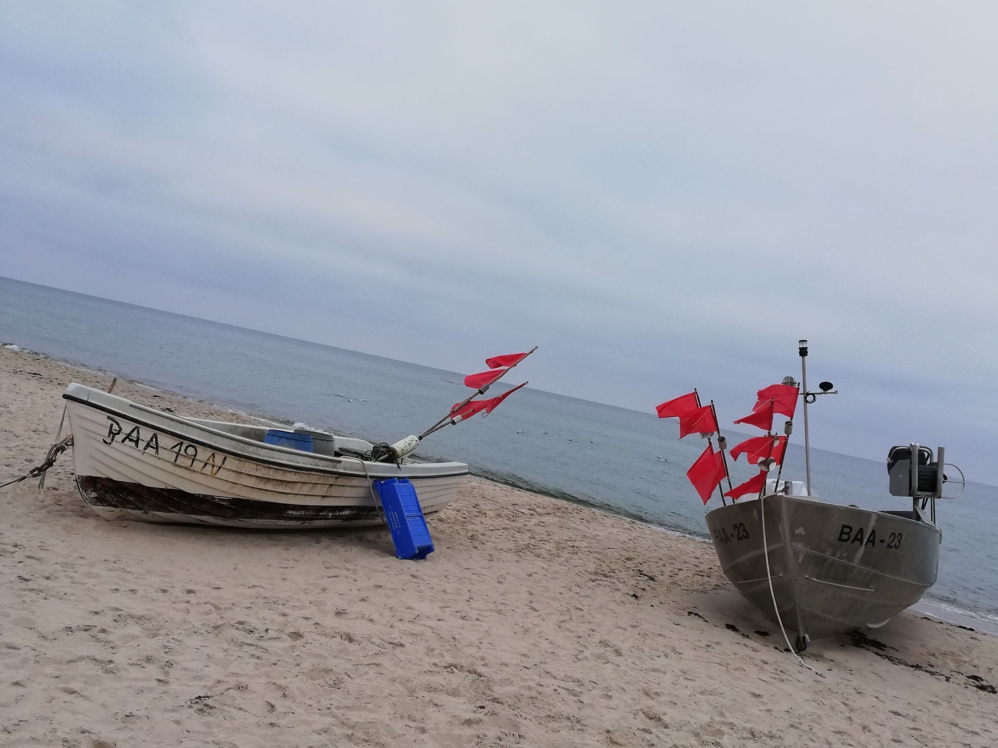 Two boats on a sandy beach with the sea in the background.
