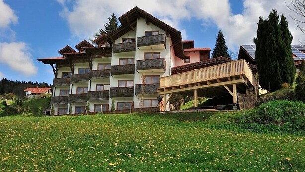 Un hotel de varios pisos con balcones y una terraza de madera.