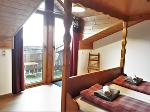 A wooden room with a sloped ceiling, a bed with a pillow and a rolled towel, and a chair. - im Bayerischen Wald inkl. aktivCard by Interhome (Sankt Englmar)