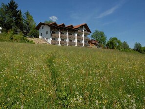 A multi-story building with balconies, situated on a hillside with a field of wildflowers. - im Bayerischen Wald inkl. aktivCard by Interhome (Sankt Englmar)