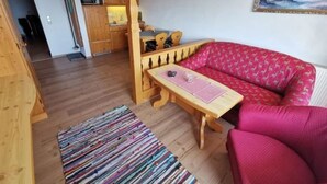Un saló acollidor amb un sofà de fusta, una taula de fusta i una catifes colorida.