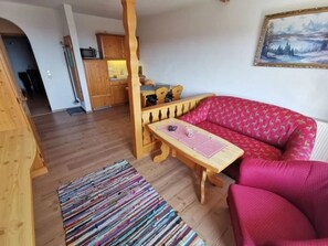 A cozy living room with a wooden sofa, a small wooden table, and a colorful rug. - im Bayerischen Wald inkl. aktivCard by Interhome (Sankt Englmar)