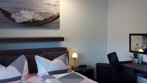 Una camera d'albergo con un letto, una scrivania, una sedia, una lampada e un quadro appeso al muro.