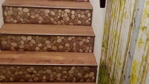 Una scala con gradini in legno e un muro decorato con un motivo verde e fogliaceo.