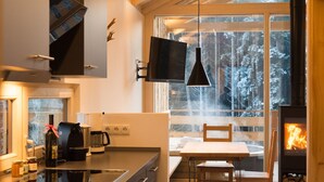 A modern kitchen with a large window, a dining area with a table and chairs, and a wood-burning stove. - Oheblick by Interhome (Regen)