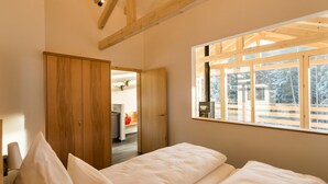 A bedroom with a large window, wooden beams, and a view of a snowy landscape. - Oheblick by Interhome (Regen)