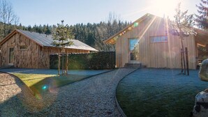 A rustic wooden cabin with a gravel path leading to a wooden deck, surrounded by a forest. - Oheblick by Interhome (Regen)