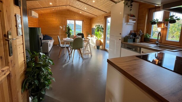 A modern kitchen with wooden cabinets, a sink, and a dining area with a table and chairs. - in Atzenhain mit Großer Terrasse by Interhome (Atzenhain)