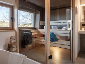 A sauna room with wooden benches, a heater, and a window providing a view of the outdoors. - EXCLUSIVE FERIENWOHNUNG MIT EIGENER SAUNA by Interhome (Regen)
