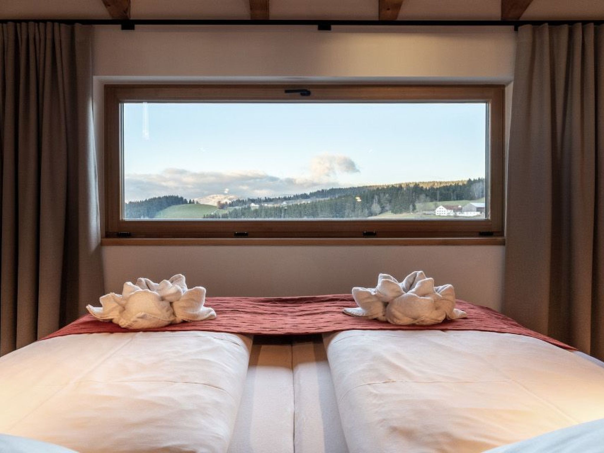Un lit double donnant sur un paysage montagneux, vu à travers une fenêtre.
