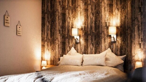 A bedroom with a wooden headboard, two bedside lamps, and a bed with pillows that say "enjoy life". - Harzgeiss by Interhome (Braunlage)